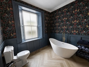 A bathroom with a freestanding bathtub, a toilet, and a window. - No.60 Sligo (Sligo)