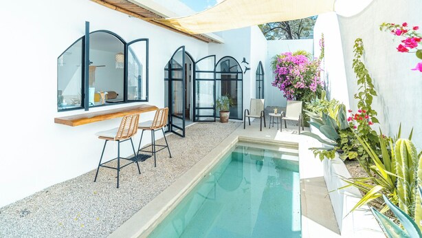 Un espace aménagé au bord de la piscine, comprenant une piscine, des sièges et des plantes en pot.