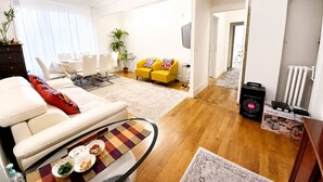 A modern living room with a sofa, coffee table, and a yellow armchair. There is a dining area with a table and chairs, and a kitchen area with appliances. - Paris 16 Michelangelo. Les Beaux Quartiers de Paris (Paris)