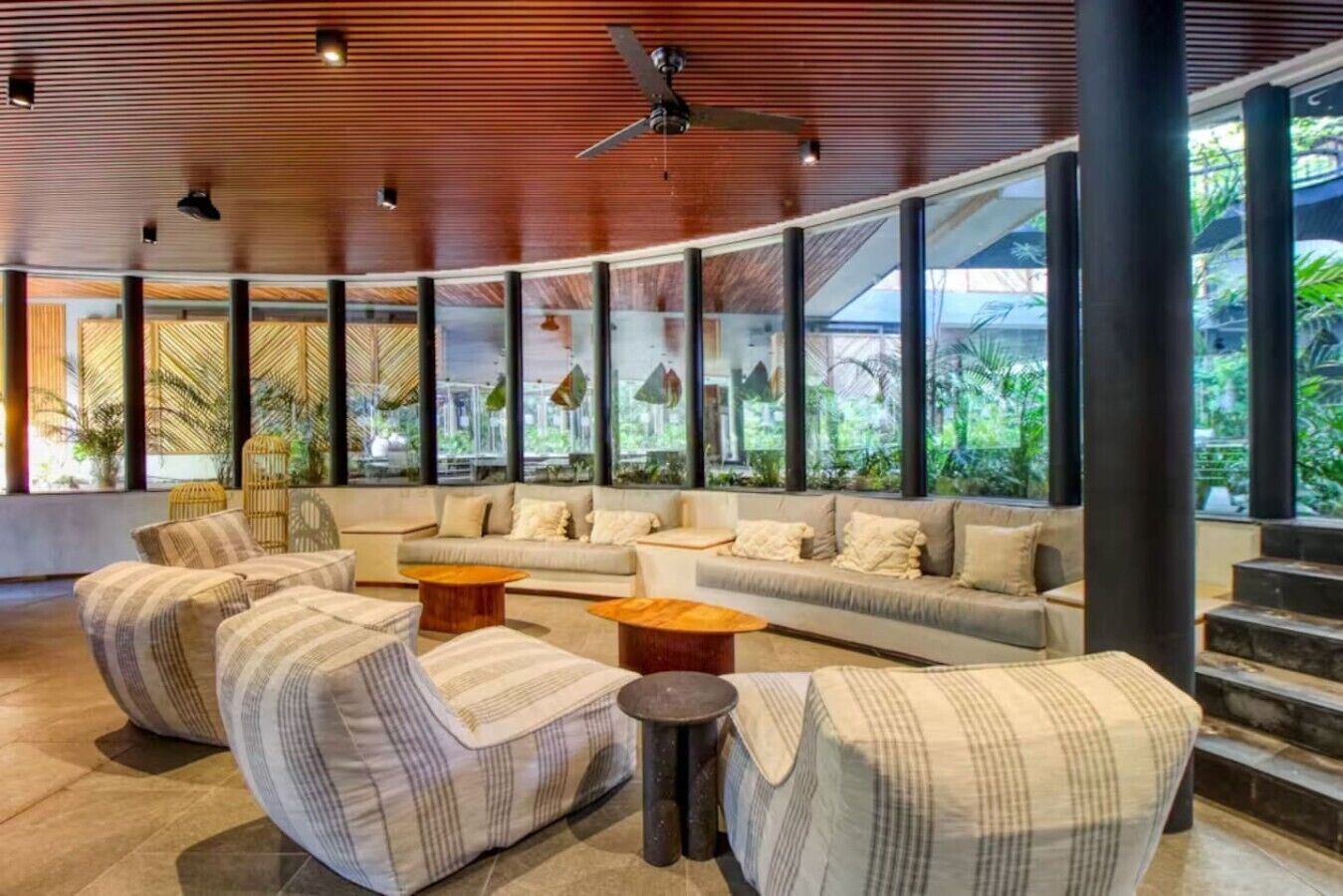 A modern lobby with a curved ceiling, large windows, and a seating area with sofas and armchairs.