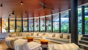 A modern lobby with a curved ceiling, large windows, and a seating area with sofas and armchairs. - Stylish Tulum Studio w/ Pool & Balcony | Sleeps 4 (Tulum)