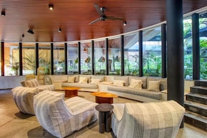 A modern lobby with a curved ceiling, large windows, and a seating area with sofas and armchairs. - Stylish Tulum Studio w/ Pool & Balcony | Sleeps 4 (Tulum)