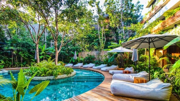 A pool with a wooden deck, lounge chairs, and umbrellas. - Stylish Tulum Studio w/ Pool & Balcony | Sleeps 4 (Tulum)