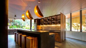 A modern kitchen with a central island, wooden bar stools, and a ceiling with linear patterns. - Stylish Tulum Studio w/ Pool & Balcony | Sleeps 4 (Tulum)