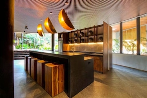 A modern kitchen with a central island, wooden bar stools, and a ceiling with linear patterns. - Stylish Tulum Studio w/ Pool & Balcony | Sleeps 4 (Tulum)