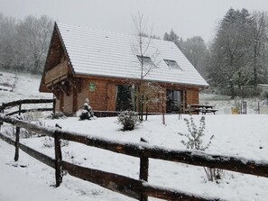 Une cabane en bois avec un toit en pente, une cour clôturée et une table de pique-nique.