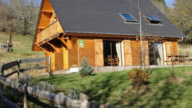 Une cabane en bois avec un toit en pente, un balcon et une petite fenêtre.