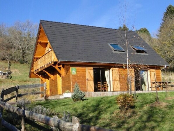 Une cabane en bois avec un toit en pente, un balcon et une petite fenêtre.