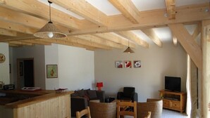 Un intérieur en bois comprenant une table à manger, des chaises, un canapé, un téléviseur et un coin cuisine.