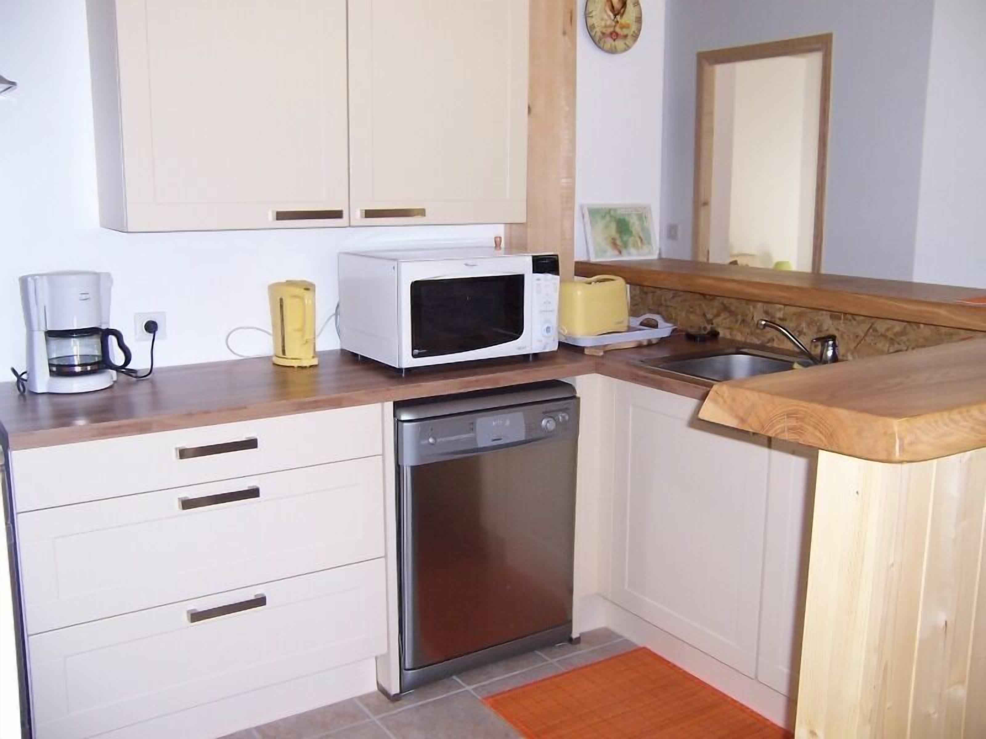 A compact kitchen with a microwave, coffee maker, and dishwasher.