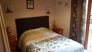 Une chambre à coucher avec un lit, une table de chevet, une lampe et une fenêtre avec des rideaux.