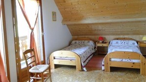 Une pièce avec deux lits en bois, une chaise et un plafond en bois.