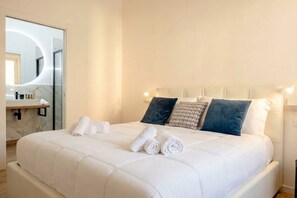 Ein Hotelzimmer mit Bett, Kissen, einem Spiegel und einem Badezimmer mit Marmorplatte.
