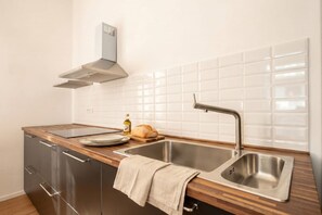 A modern kitchen with a stainless steel sink, wooden countertop, and a built-in oven. - Maison Manzoni - Contemporary Elegance (Bari)