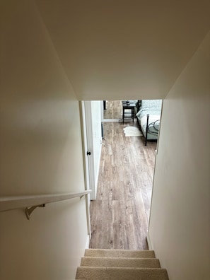 A staircase leading to a room with a bed, a bedside table, and a patterned bedspread. - Modern Abbotsford Retreat | Private Suite Near Downtown | Sleeps 4 (Abbotsford)