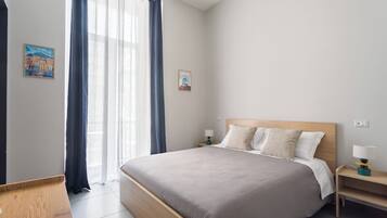 Quarto de hotel moderno com uma cama grande, mesas de cabeceira e uma janela com cortinas.