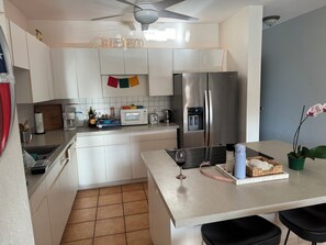 A modern kitchen with white cabinets, a stainless steel refrigerator, a microwave, and a coffee maker. - Ocean Sunset Lover (Isabela)