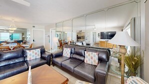 Una sala de estar con un sofá, una mesa de centro, una lámpara y un espejo grande.