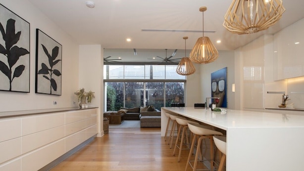 A modern kitchen with a central island, pendant lighting, and artwork on the walls. - Margaret House | Elegant City-Fringe Escape (North Adelaide)