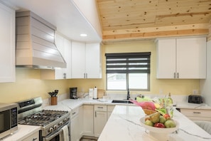 A modern kitchen with white cabinets, a stainless steel stove, and a marble countertop.