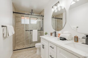Une salle de bain moderne équipée d’une douche, de toilettes et d’un meuble-lavabo avec un miroir et un évier.