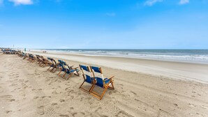Une plage bordée de rangées de chaises de plage bleues et blanches.