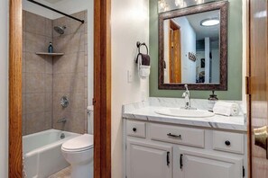 Un baño con bañera, inodoro y tocador con espejo.