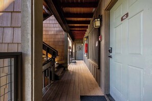 Un pasillo con suelo de madera, una escalera y una puerta marcada con el número 112.