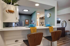 Una cocina moderna con una isla central, taburetes de bar y un reloj en la pared.