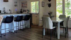 A modern kitchen with a bar area, dining chairs, and a table.