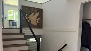 A staircase with wooden steps and black handrails, leading to a room with a white wall and a map.