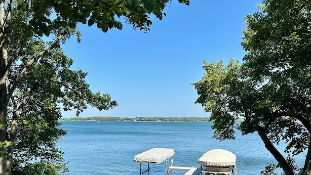 A lakeside setting with Adirondack chairs, a covered dock, and a boat house.