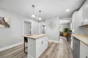 A modern kitchen with white cabinetry, a granite countertop, and pendant lighting. - 3-BR Renovated Bungalow—River District—Fire Pit! (Mount Holly)