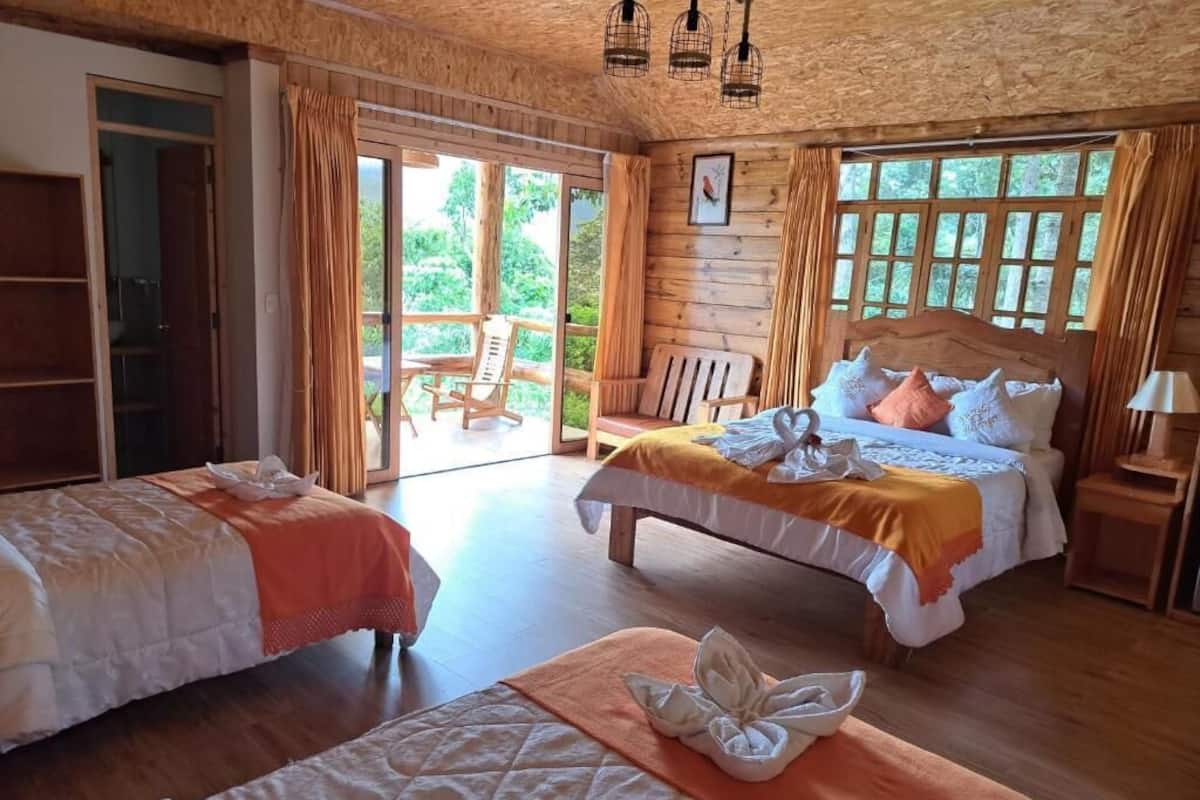 Une chambre avec deux lits, un plafond en bois et une porte-fenĂȘtre coulissante donnant sur un espace extĂ©rieur.
