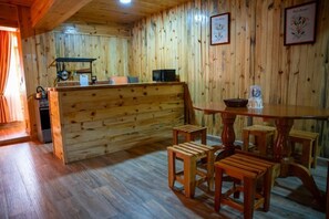 A wooden interior with a kitchen area, wooden stools, and a table. - Fundo Hassinger Oxapampa (Oxapampa)