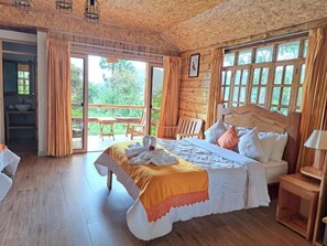 A wooden cabin bedroom with a bed, a bench, a table, and a view of the outdoors. - Fundo Hassinger Oxapampa (Oxapampa)
