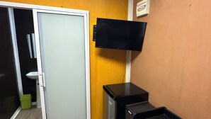 Een kamer met een schuifdeur, een wandtelevisie, een klein bureau en een archiefkast.