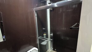 Een badkamer met toilet, bidet en een douchecabine met glazen wanden.