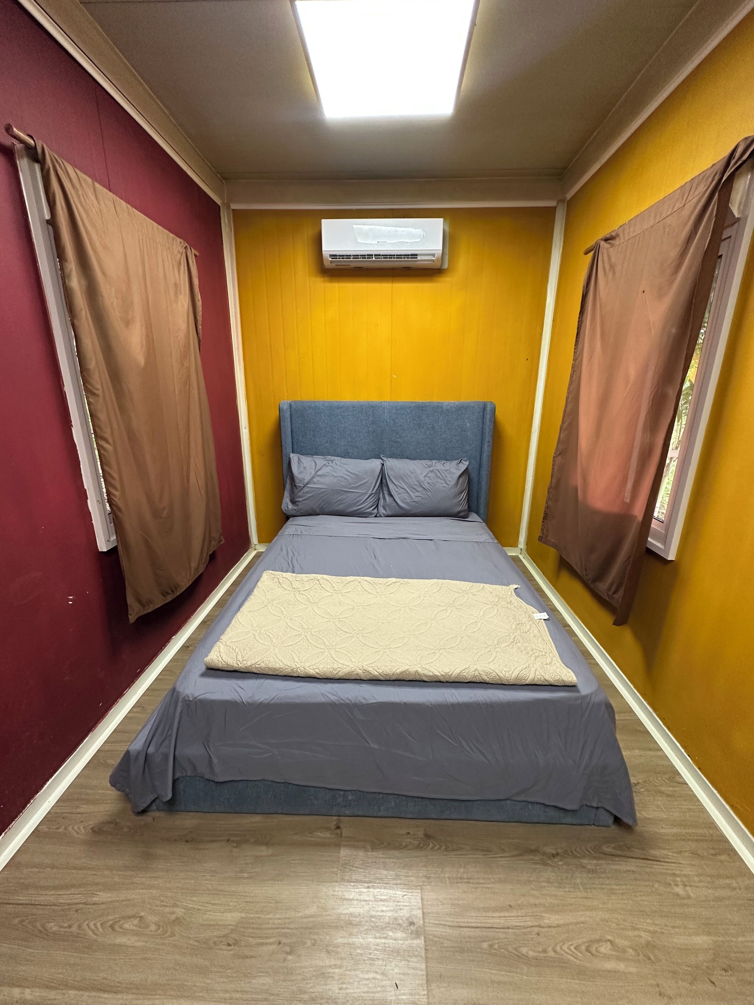 A bedroom with a bed, a window, and an air conditioning unit.
