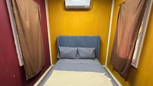 Een slaapkamer met een bed, een raam en een airconditioning.