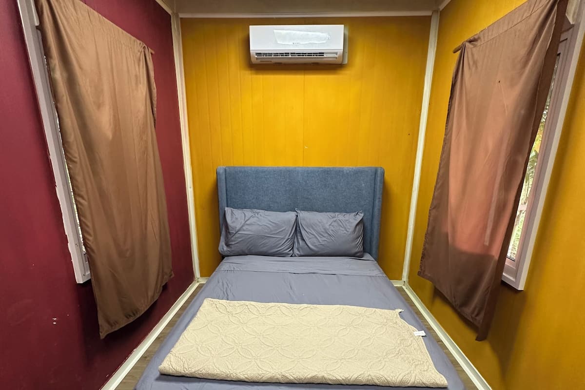 Une chambre à coucher avec un lit, une fenêtre et un appareil de climatisation.