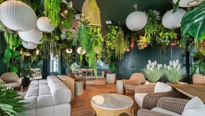Un salón moderno con plantas colgantes, muebles de mimbre y una mesa de centro de madera.