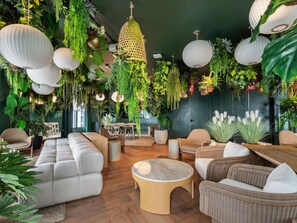Eine moderne Lounge mit hängenden Pflanzen, Korbmöbeln und einem Holztisch.