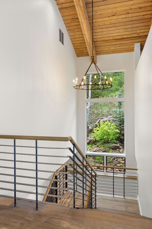 A staircase with wooden railings and a metal handrail, leading to a room with a wooden ceiling and a view of greenery outside. - Elegant Snowmass Village Family Escape W/ Hot Tub, 2 Decks, Luxury Finishes | Snowmass Classic (Snowmass Village)