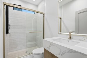 A modern bathroom with a glass-enclosed shower, a white toilet, and a marble vanity with a large mirror. - Fully Custom New Construction In the Heart of Midtown (Atlanta)