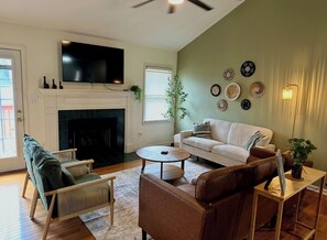 A living room with a fireplace, a television, a sofa, and a coffee table. - 3-bedroom house near Downtown Fountain Inn (Fountain Inn)