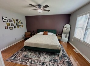 A bedroom with a bed, a ceiling fan, a rug, a dresser, a mirror, and a window. - 3-bedroom house near Downtown Fountain Inn (Fountain Inn)