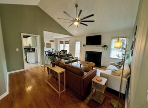 A spacious living room with a fireplace, a ceiling fan, and a television. - 3-bedroom house near Downtown Fountain Inn (Fountain Inn)