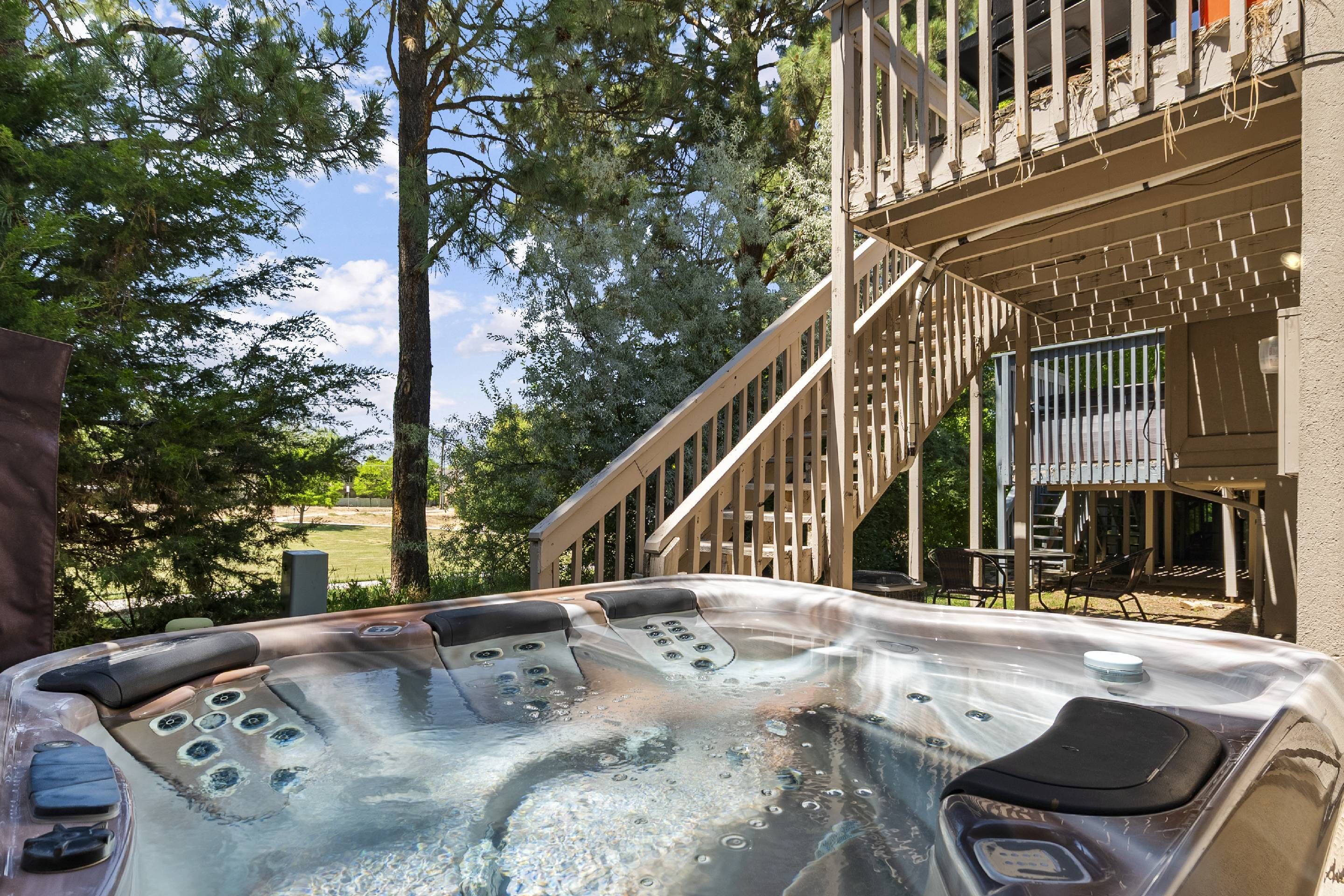A hot tub with controls, surrounded by trees and a wooden deck.