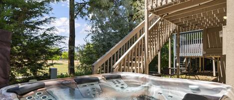 A hot tub with controls, surrounded by trees and a wooden deck.